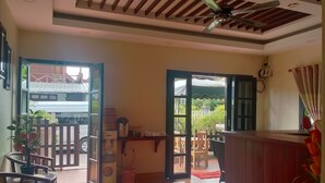 Habitación con suelo de madera, ventilador de techo y vista a un edificio tradicional.