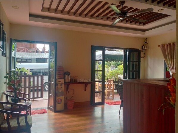 A room with wooden flooring, a ceiling fan, and a view of a traditional building outside.