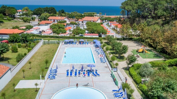 A swimming pool with sun loungers and umbrellas, surrounded by houses and a view of the sea. - St Jean Luz Hotel Erromardie Suite 4p (Saint-Jean-de-Luz)