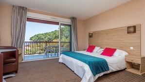 A hotel room with a bed, a desk, and a balcony with a view of trees. - St Jean Luz Hotel Erromardie Suite 4p (Saint-Jean-de-Luz)