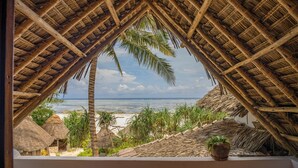 A thatched-roof structure with a view of the beach and palm trees. - Zoi Retreat Hotel Zanzibar (Matemwe)