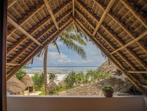 A thatched-roof structure with a view of the beach and palm trees. - Zoi Retreat Hotel Zanzibar (Matemwe)