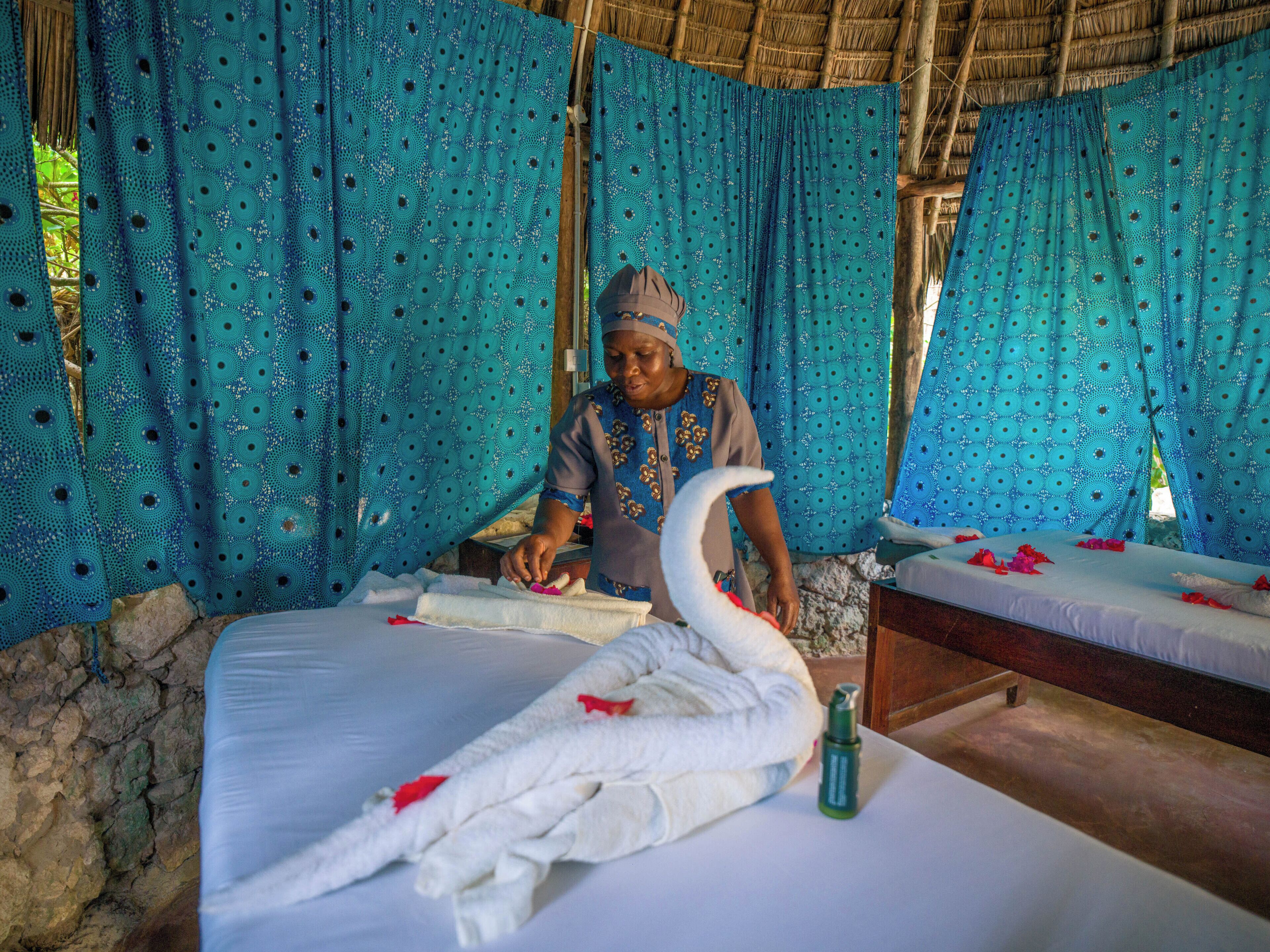 A room with a bed, a large swan decoration, and a person working.