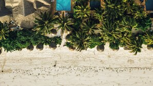 An aerial view of a resort with multiple pools, palm trees, and a beach area. - Zoi Retreat Hotel Zanzibar (Matemwe)