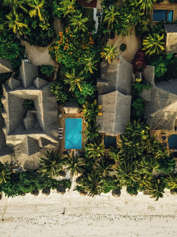 An aerial view of a resort with multiple pools, palm trees, and a beach area. - Zoi Retreat Hotel Zanzibar (Matemwe)