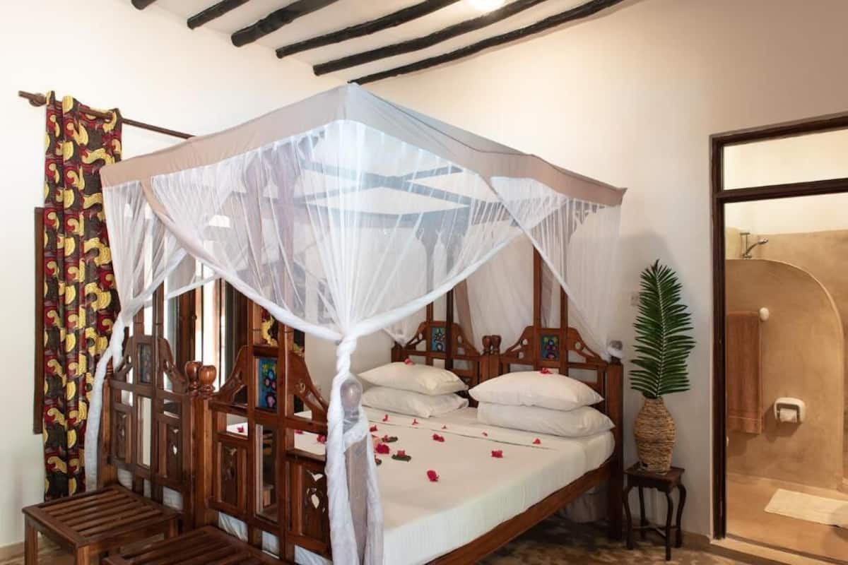A traditional wooden bed with a canopy, a small wooden chair, and a potted plant.