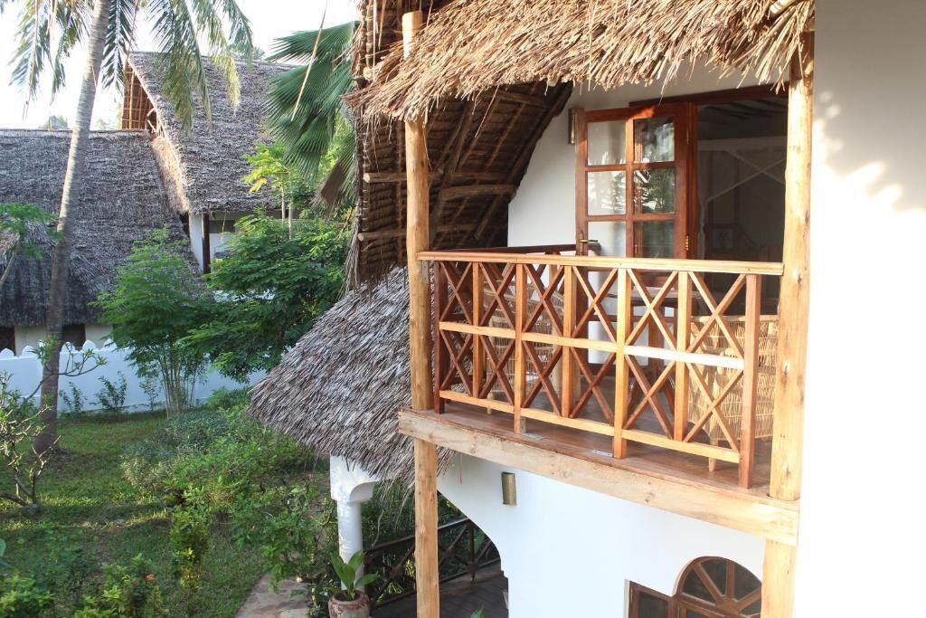 Una casa tradicional con techo de paja, balcón de madera y paredes blancas.