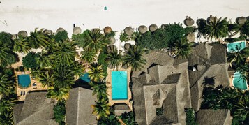 Vista aérea de un resort con varias piscinas, palmeras y zonas de playa.
