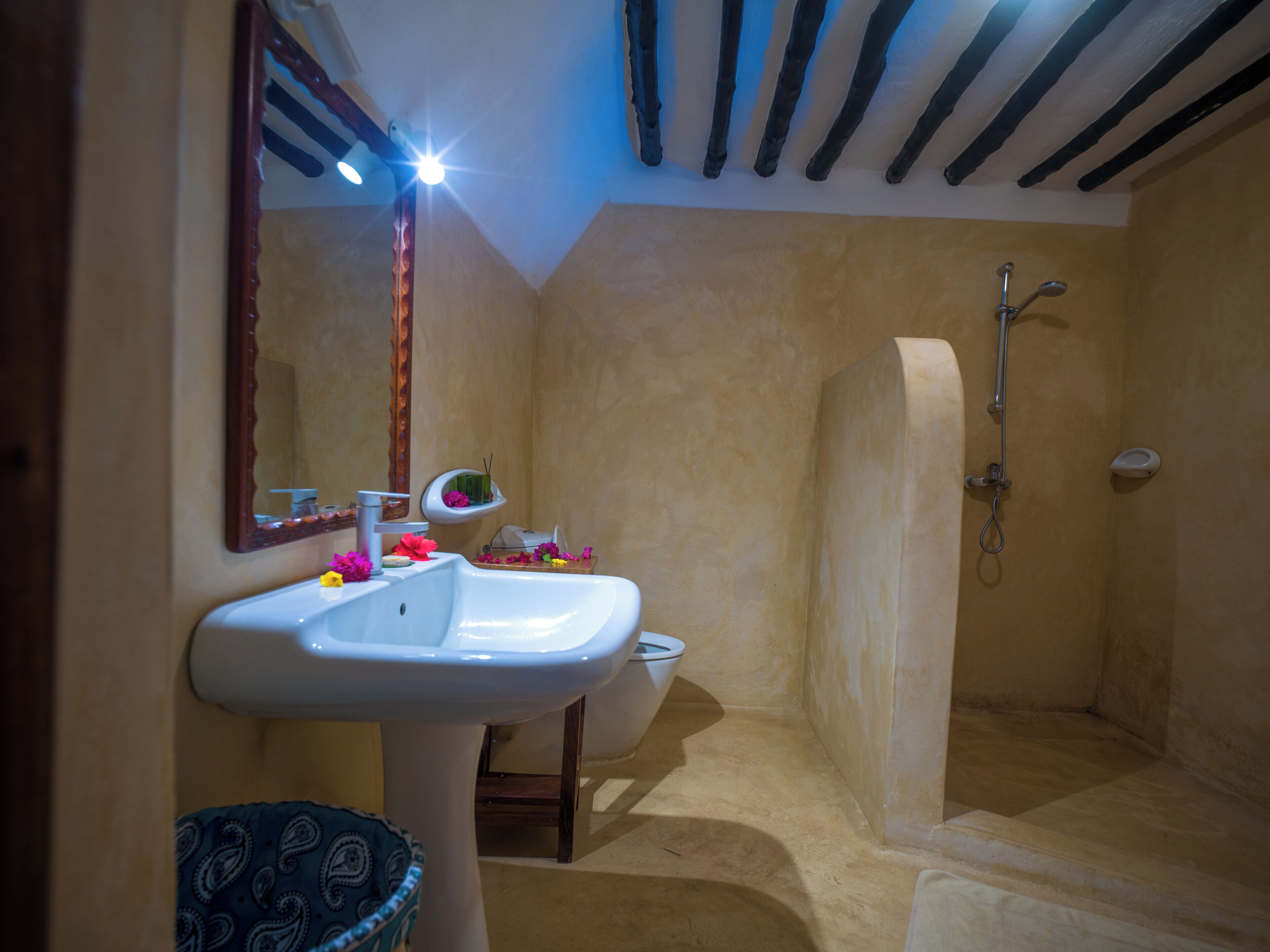 Un baño con lavabo, espejo, ducha y un pequeño estante con artículos de aseo.