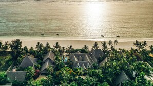 A beach resort with thatched-roof huts, palm trees, and a view of the ocean. - Zoi Retreat Hotel Zanzibar (Matemwe)