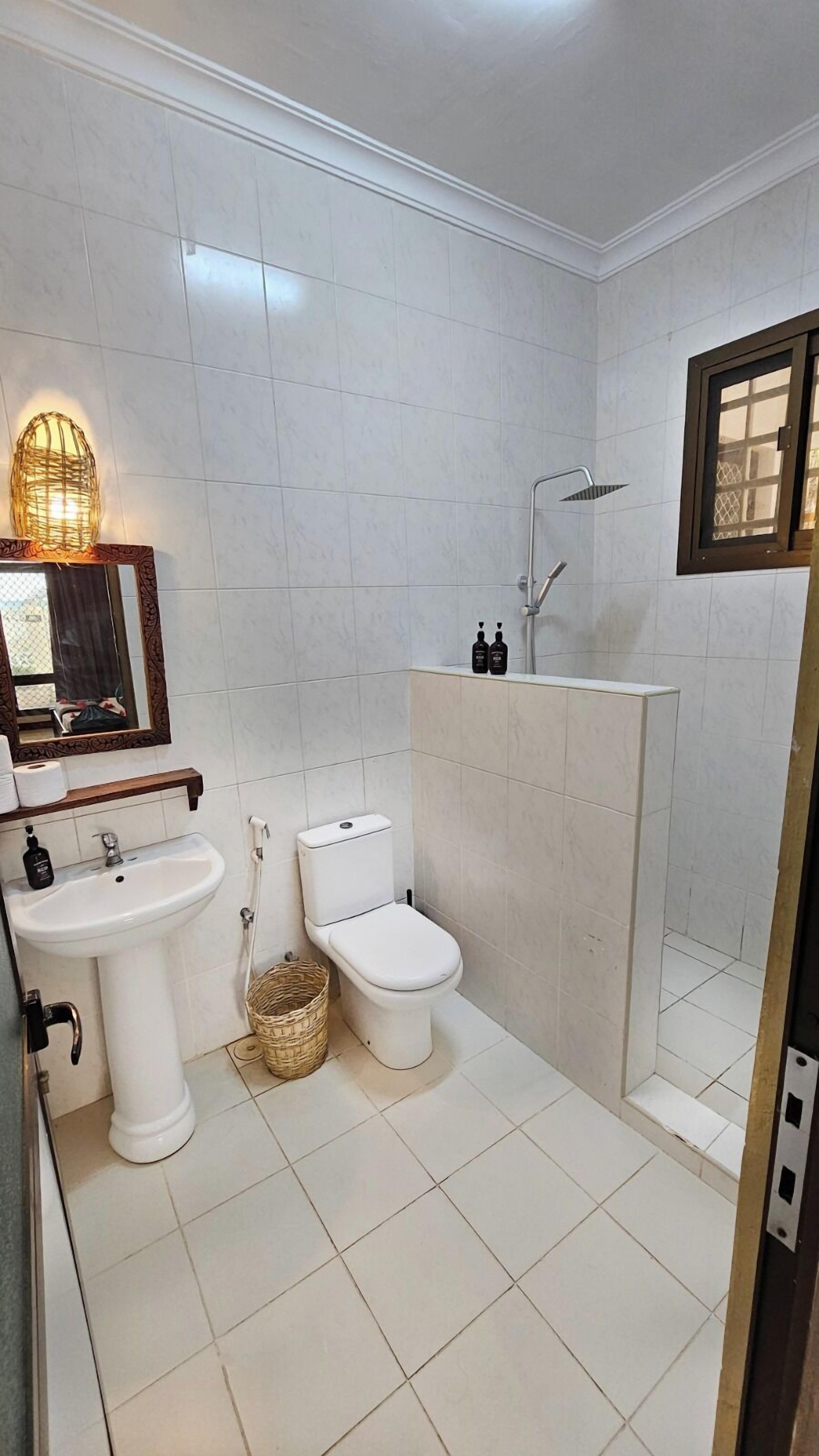 Un baño con lavamanos, inodoro y zona de ducha.