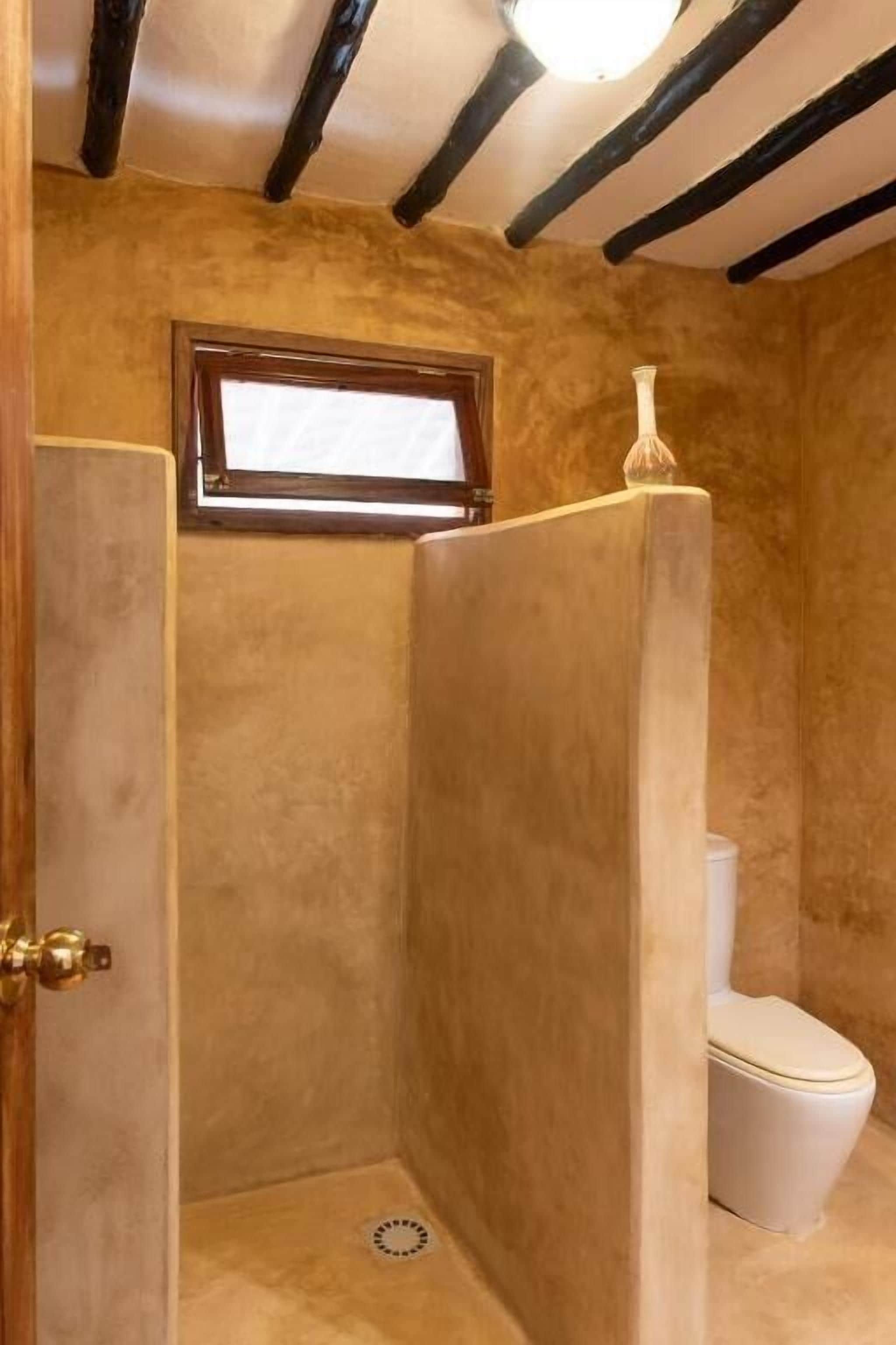 Un baño con cabina de ducha, inodoro y ventana.