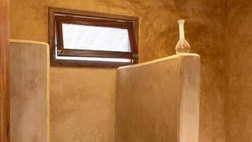 Un baño con cabina de ducha, inodoro y ventana.