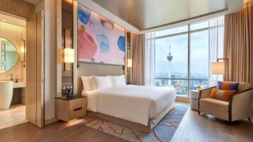 A modern hotel room with a large bed, a sitting area with a chair, a view of the cityscape, and a large abstract painting on the wall.