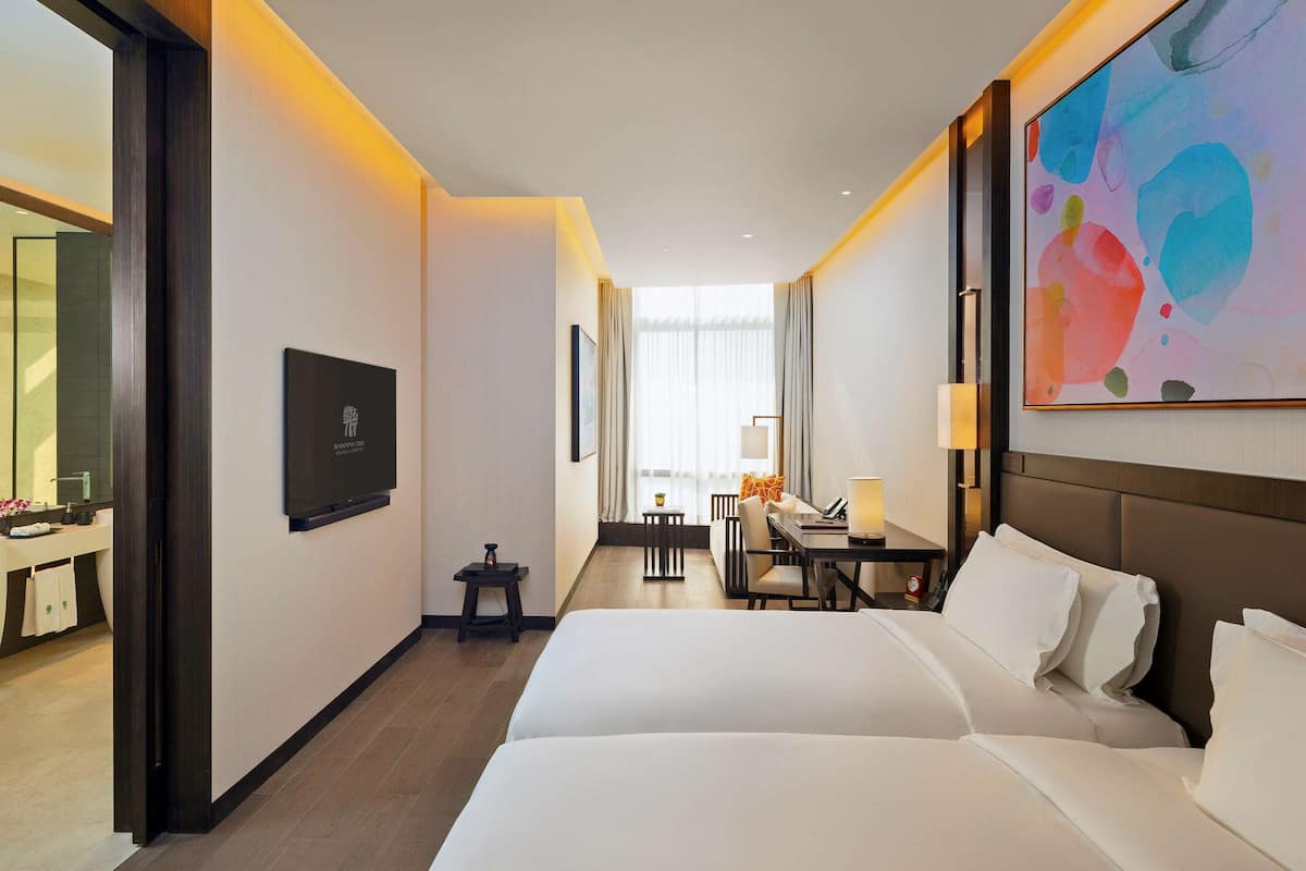 Habitación de hotel con una cama grande, un escritorio, una silla, un televisor y un cuadro en la pared.