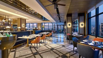 A modern restaurant with a high ceiling, marble flooring, and a city view.