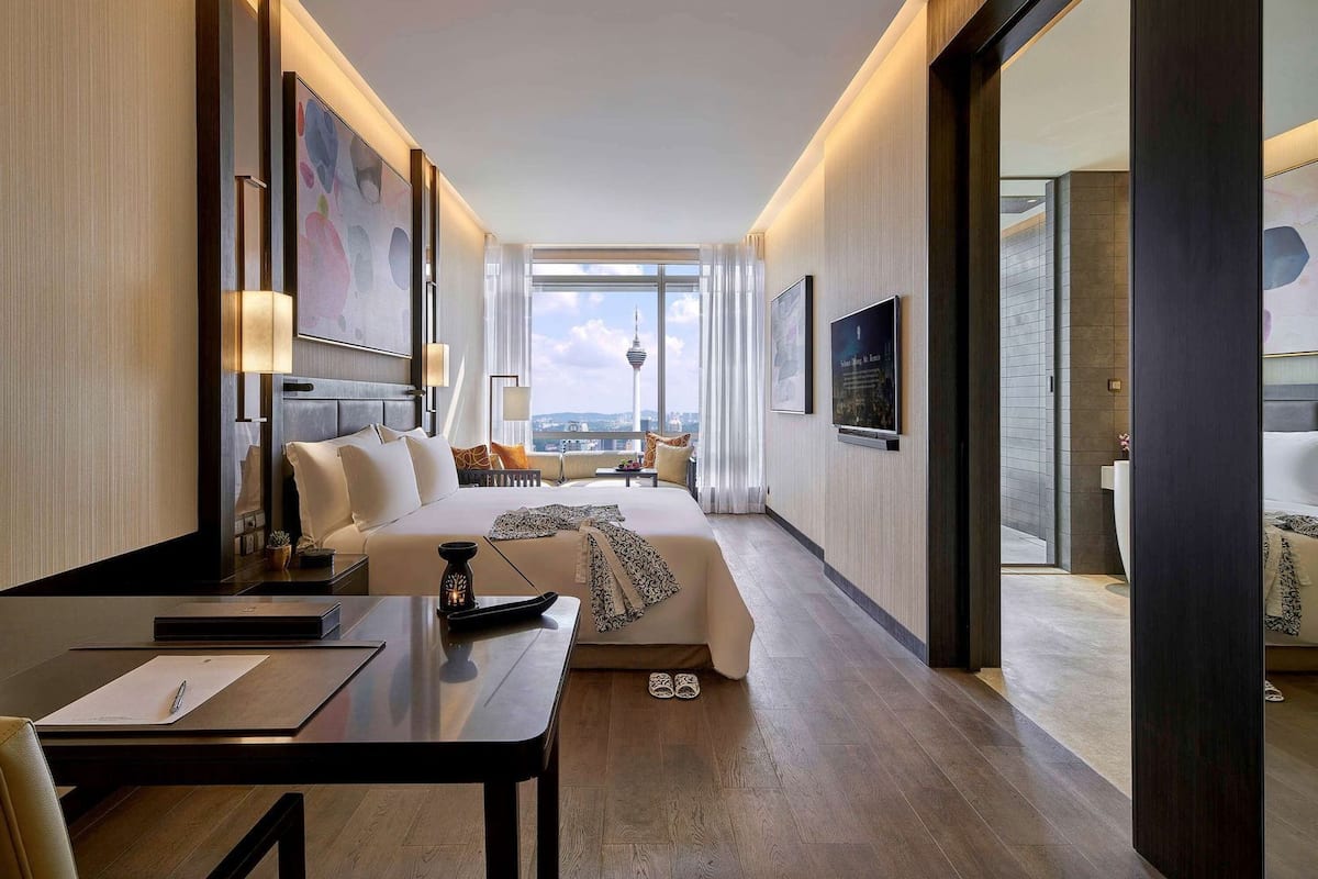 Habitación de hotel con una cama grande, un escritorio, un televisor y vistas a una torre.