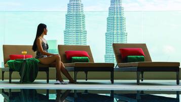 A person relaxing by a pool with a view of the Petronas Towers.
