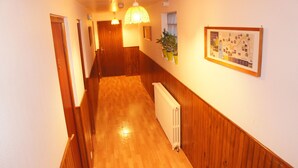 A hallway with wooden flooring, a white radiator, and a framed map on the wall. - Hôtel de la place (Germigny-des-Pres)