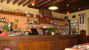 A bar area with wooden beams, a counter with various bottles, a foosball table, and a menu on the wall. - Hôtel de la place (Germigny-des-Pres)