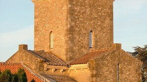 A historic stone church with a prominent bell tower and arched windows. - Hôtel de la place (Germigny-des-Pres)