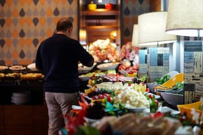 Un bufé con diversos alimentos y una persona sirviendo.