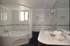Un baño con bañera, lavamanos, espejo y ventana.