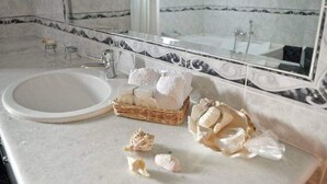 A bathroom with a marble sink, a large mirror, and a wicker basket with toiletries. - Villa Dimeon (West Achaea)