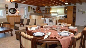 A dining area with a round table set for six, surrounded by wooden chairs. - Villa Dimeon (West Achaea)