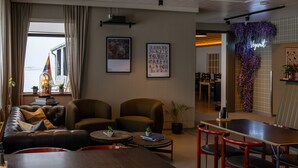 A modern lounge area with leather sofas, a wooden table, and red chairs. There are framed artworks on the walls and a neon sign that reads "Veganist." -  Hotel Snaefellsnes - formally Hotel Rjukandi (Eyja- og Miklaholtshreppur)