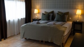 A neatly made bed with a green blanket, two bedside lamps, and a window with curtains. -  Hotel Snaefellsnes - formally Hotel Rjukandi (Eyja- og Miklaholtshreppur)