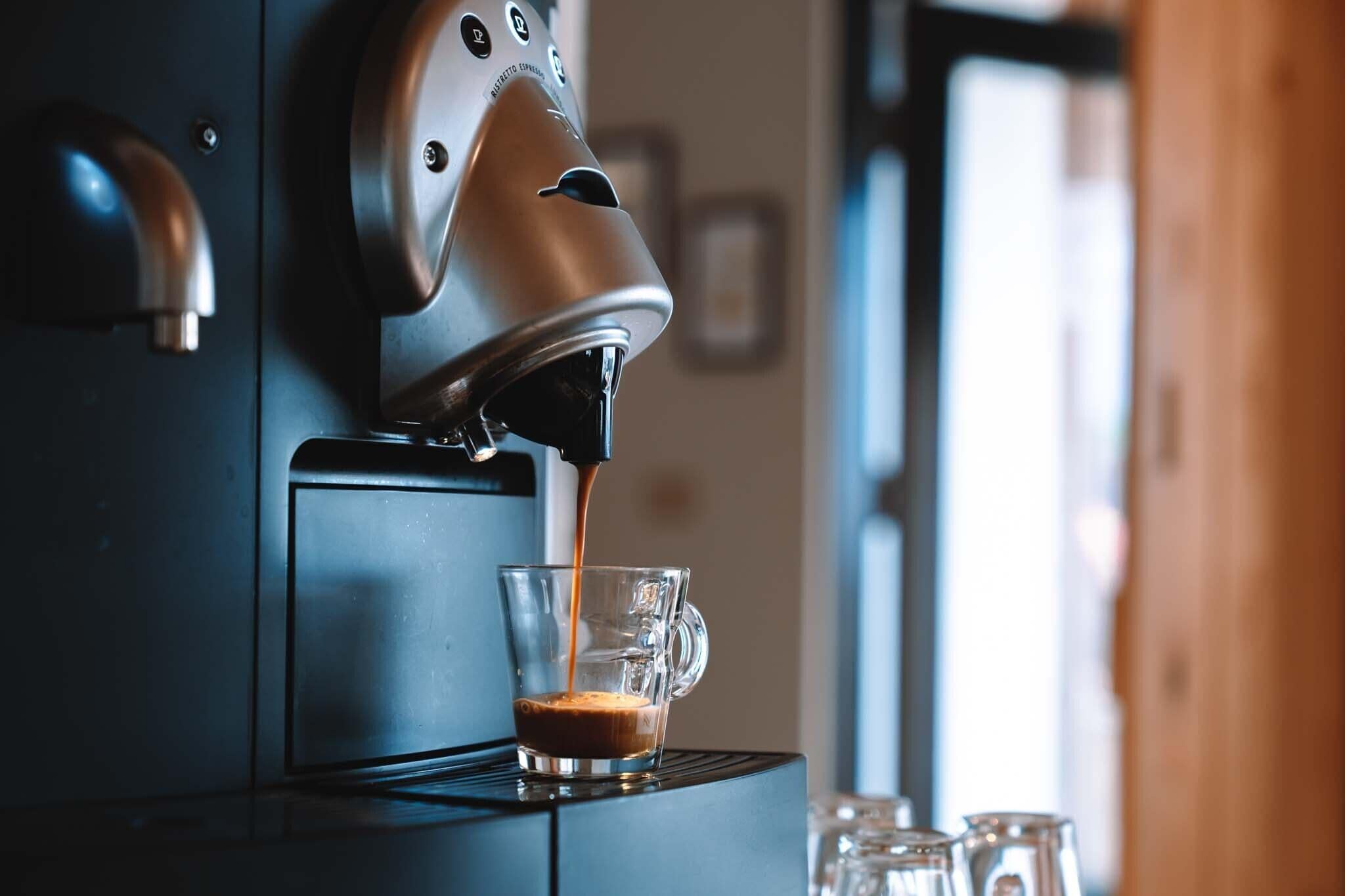Eine Kaffeemaschine füllt Kaffee in ein Glas.