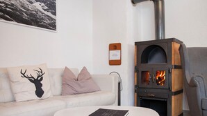 Ein modernes Wohnzimmer mit einem weißen Sofa, dekorativen Kissen, einem runden weißen Couchtisch und einem Kaminofen.