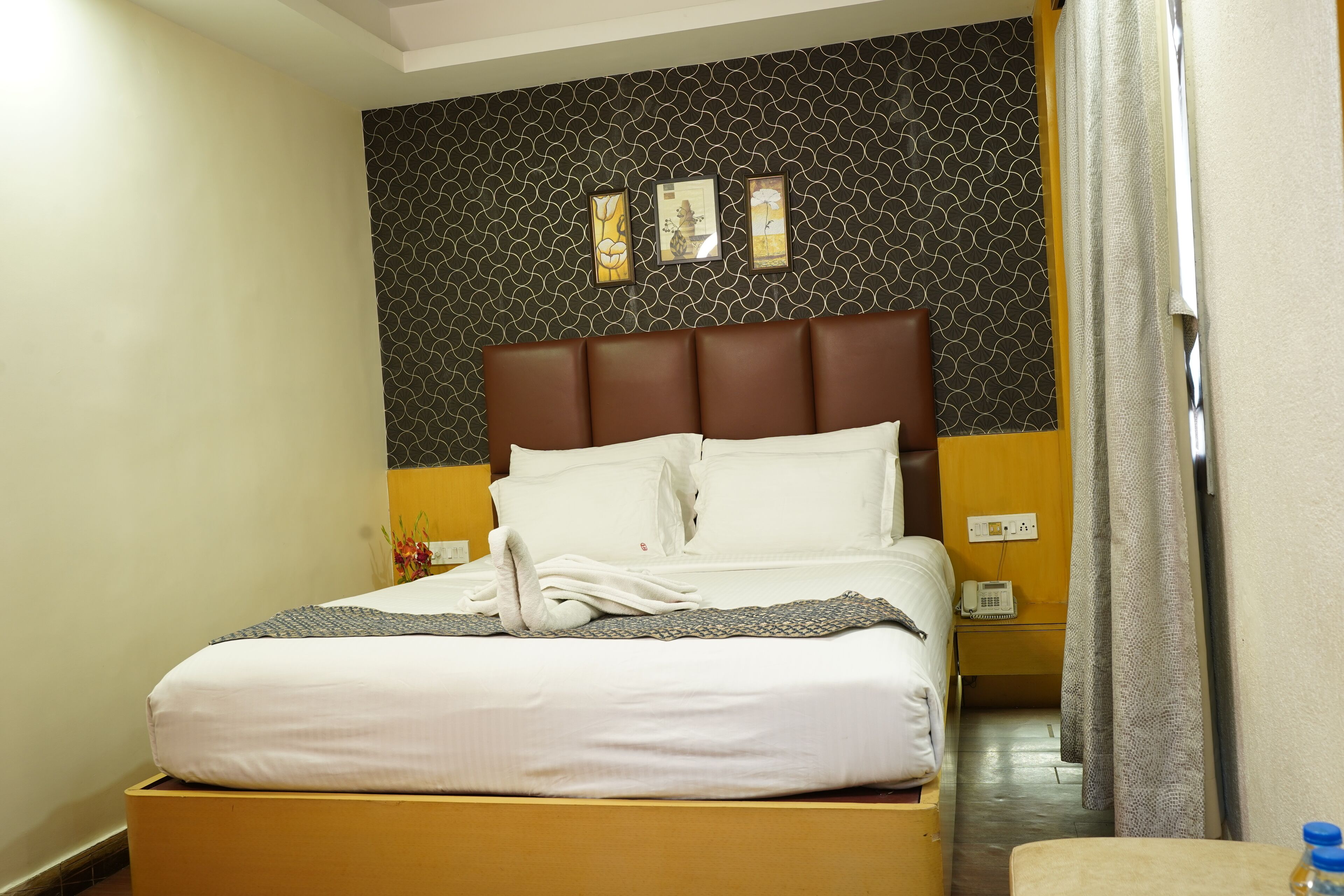 A neatly made bed with white linens, a brown headboard, and a wall with a geometric pattern.