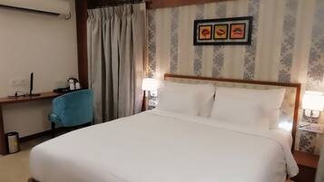 Une chambre d’hôtel avec un grand lit, un bureau avec une chaise, une lampe et un tableau au mur.