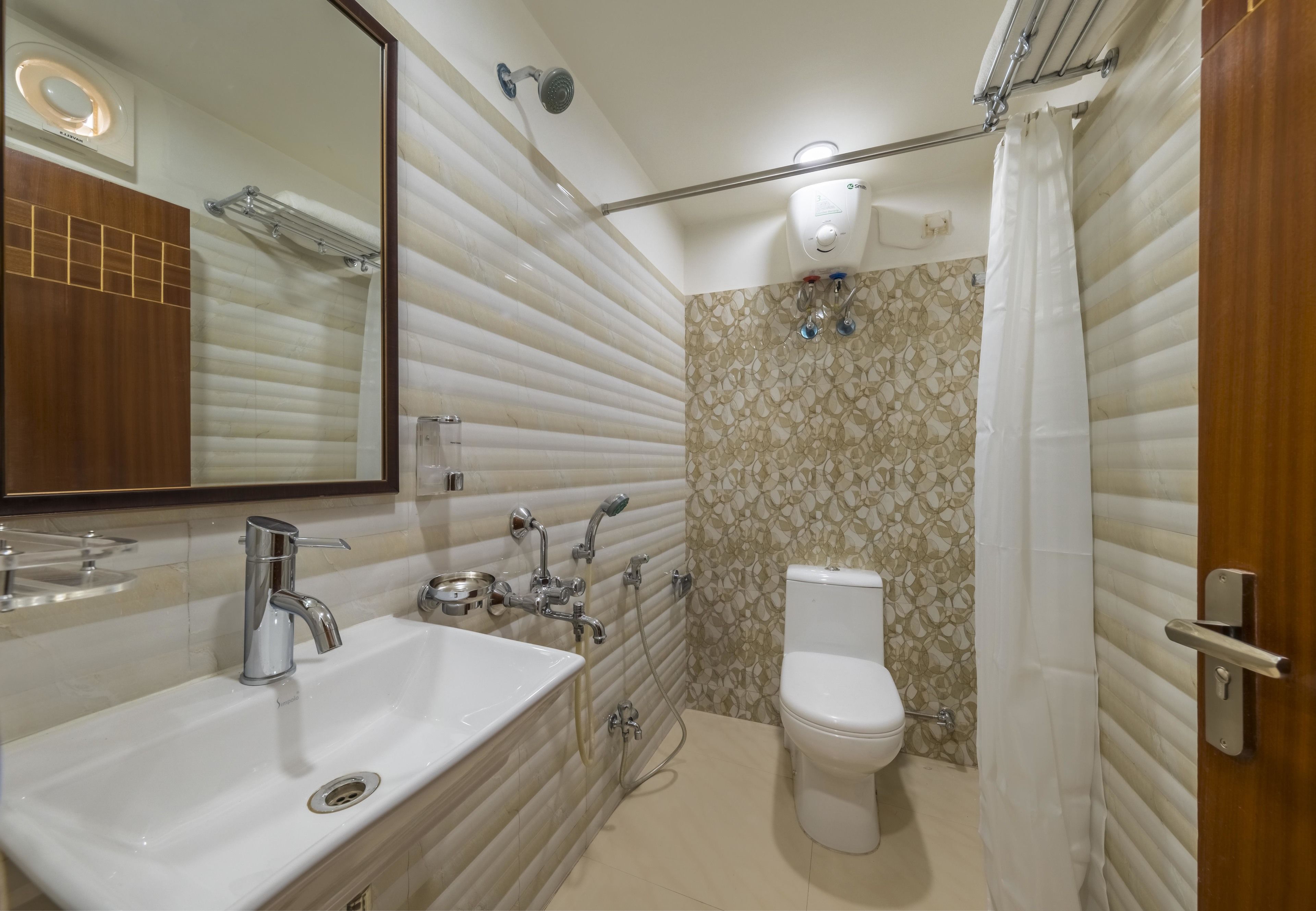 Un baño moderno con lavamanos, espejo, inodoro, ducha y toallero.