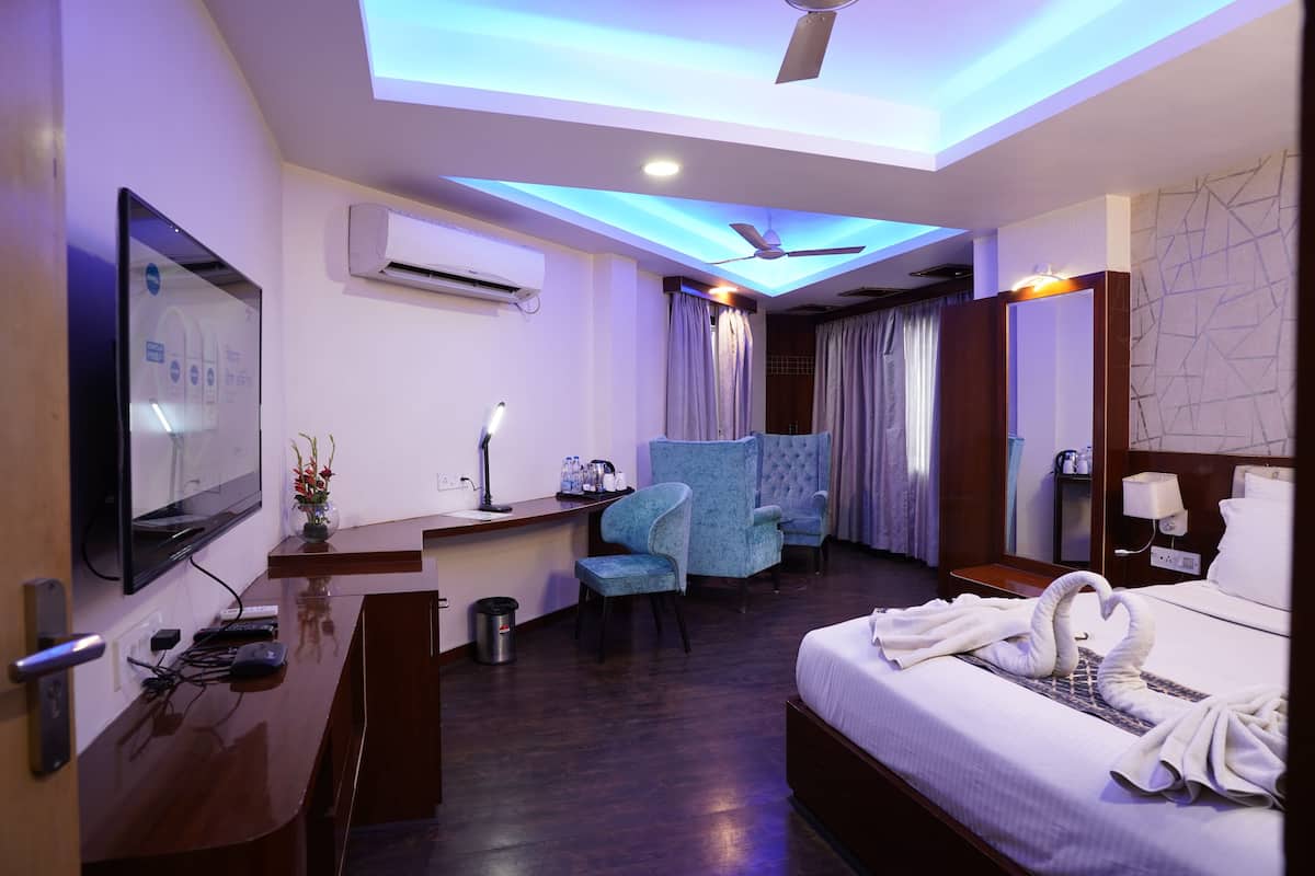 A hotel room with a bed, a desk, a chair, a TV, and a ceiling fan.