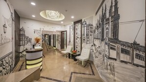 Un vestíbulo de hotel con una imponente escalera, un mostrador de recepción y una zona de estar.