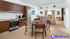 Una cocina moderna con armarios de madera, horno empotrado y una zona de comedor con una mesa redonda y sillas.