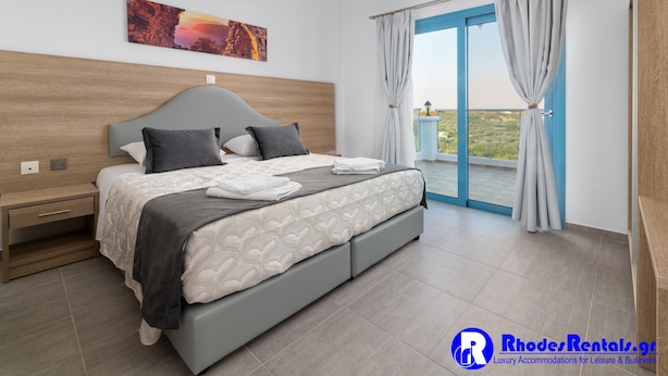 Un dormitorio moderno con una cama grande, una mesita de noche, una ventana con cortinas y vistas a zonas verdes.