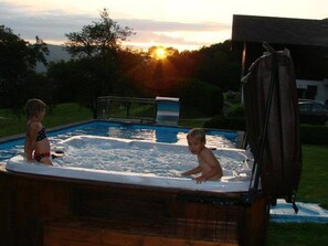Een jacuzzi met twee personen, omgeven door gras en bomen.