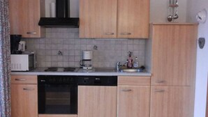 Een keuken met houten kastjes, een vaatwasser, een oven, een koffiezetapparaat en een spoelbak.