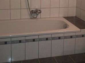 Een badkamer met een bad, douche en toilet.