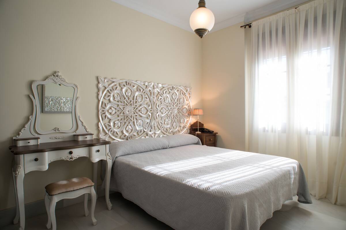 A bedroom with a bed, a dresser, a mirror, and a lamp.