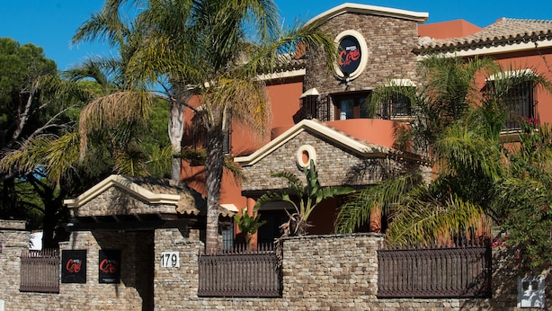 A hotel with a stone facade, palm trees, and a sign reading "Hotel Cortez." - Hotel Coral Playa (Chiclana de la Frontera)