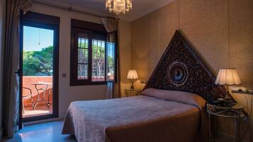 A bedroom with a large bed, a chandelier, and a view of the outdoors through a sliding door.
