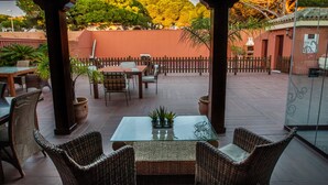 An outdoor patio with wicker furniture, a glass table, and potted plants. - Hotel Coral Playa (Chiclana de la Frontera)