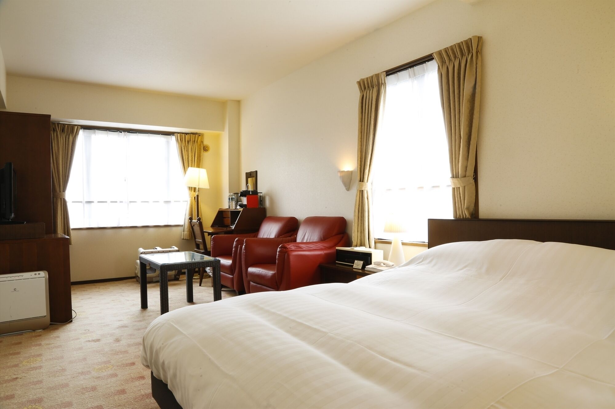 Una habitación de hotel con una cama grande, un escritorio, una silla y un televisor.