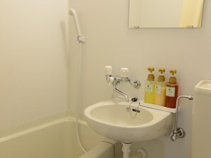 Ein Badezimmer mit einem weißen Waschbecken, einer Dusche und drei Seifenflaschen.