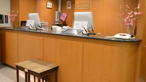 Una recepción con dos monitores de computadora, un teléfono y una pequeña mesa.